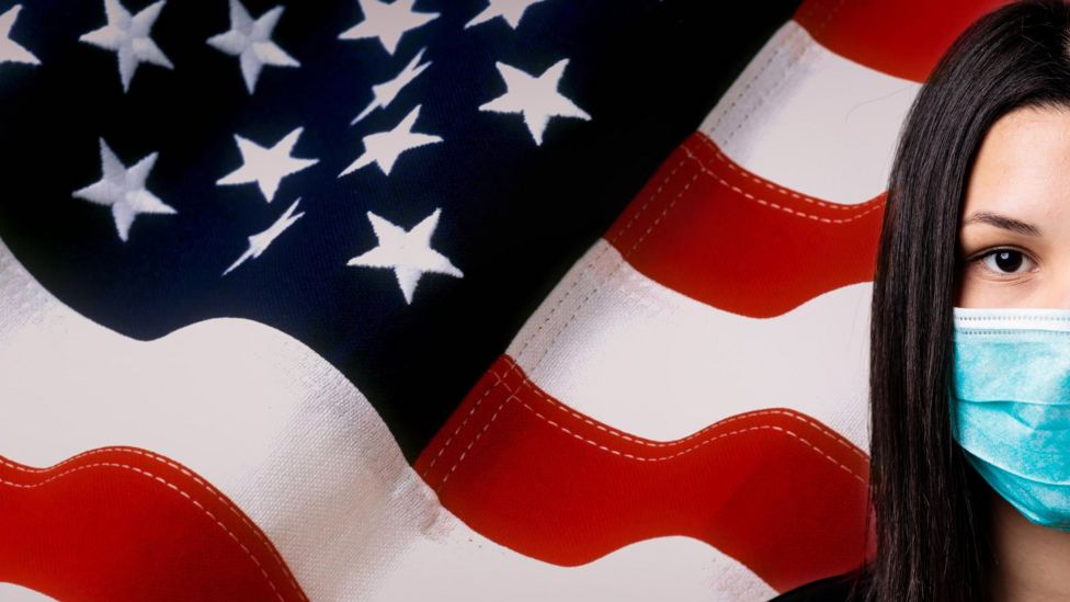 A file photo of a masked Asian woman in front of an American flag