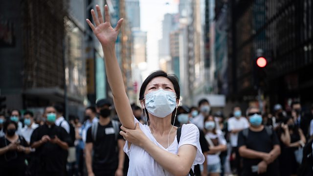 A masked woman raises her hand during a protest in Hong Kong